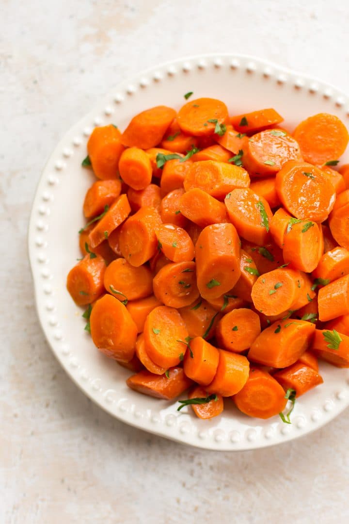 honey glazed carrots on a white plate with chopped fresh parsley