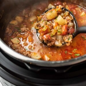 an instant pot with a ladle of hamburger soup