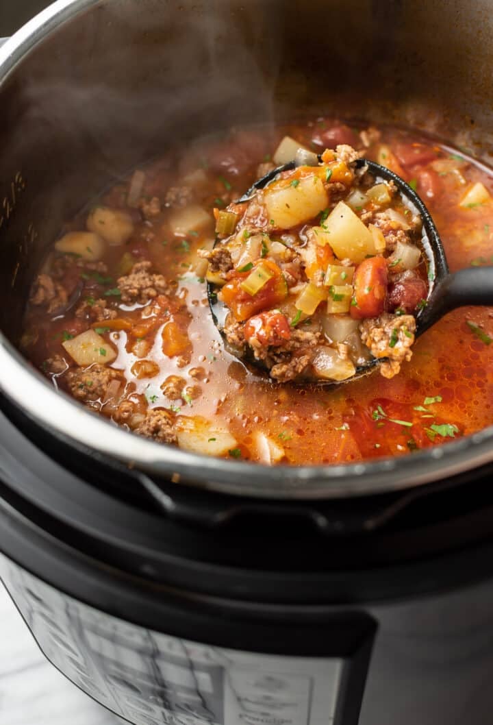 an instant pot with a ladle of hamburger soup