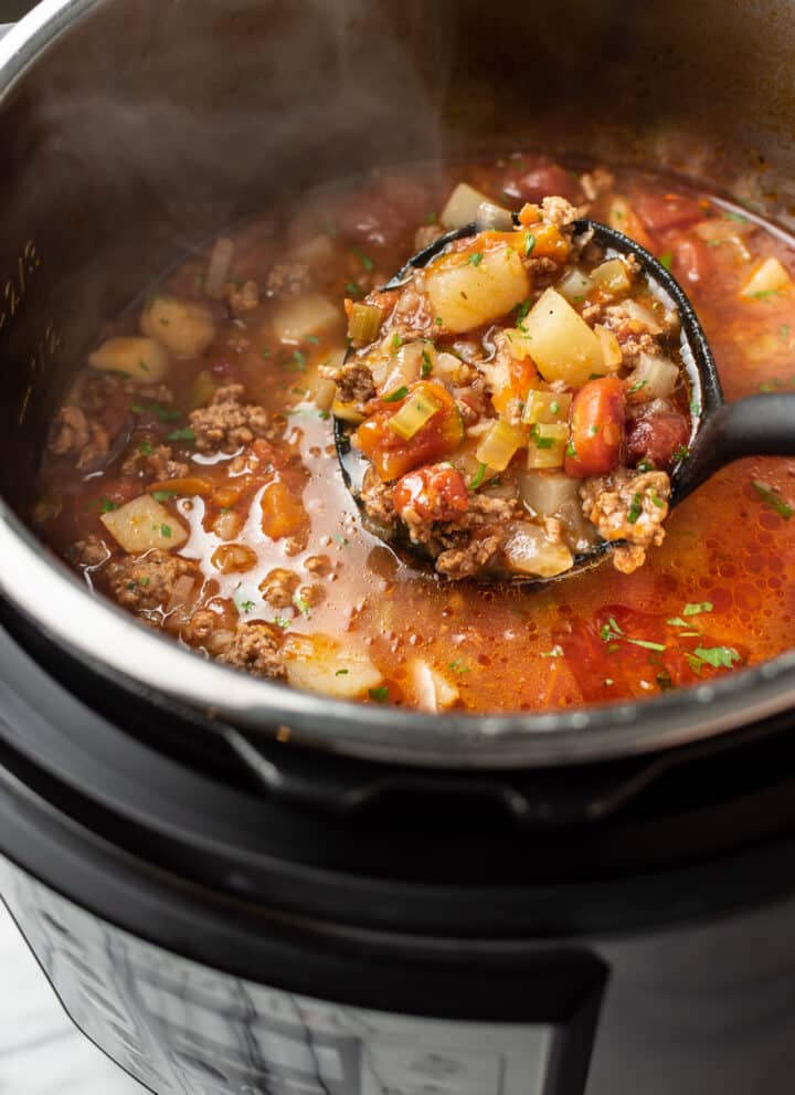 an instant pot with a ladle of hamburger soup