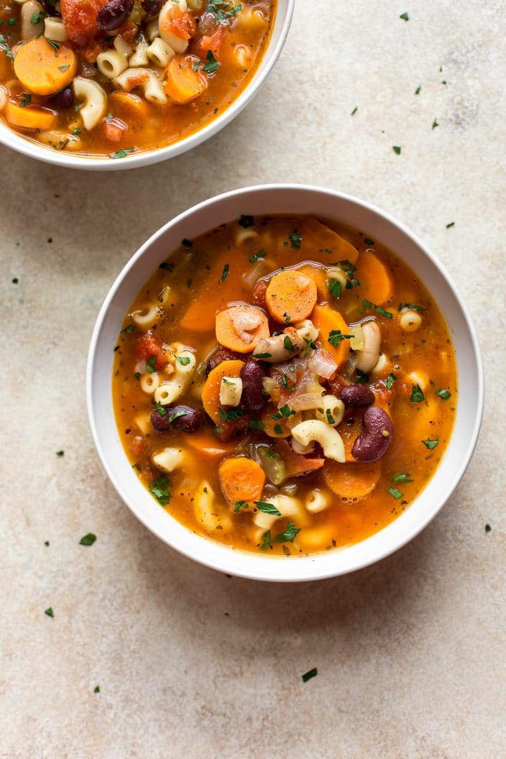 Instant Pot pasta e fagioli soup with vegetables, pancetta, beans, pasta, and a tomato broth in two white bowls