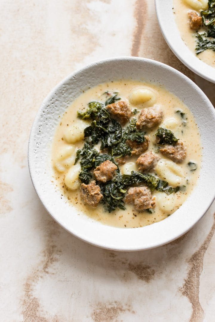 white bowl with creamy gnocchi soup with sausage and kale