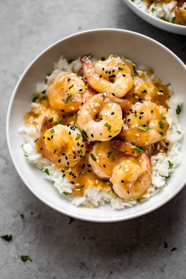 white bowl with several ginger garlic soy sauce shrimp over a bed of rice