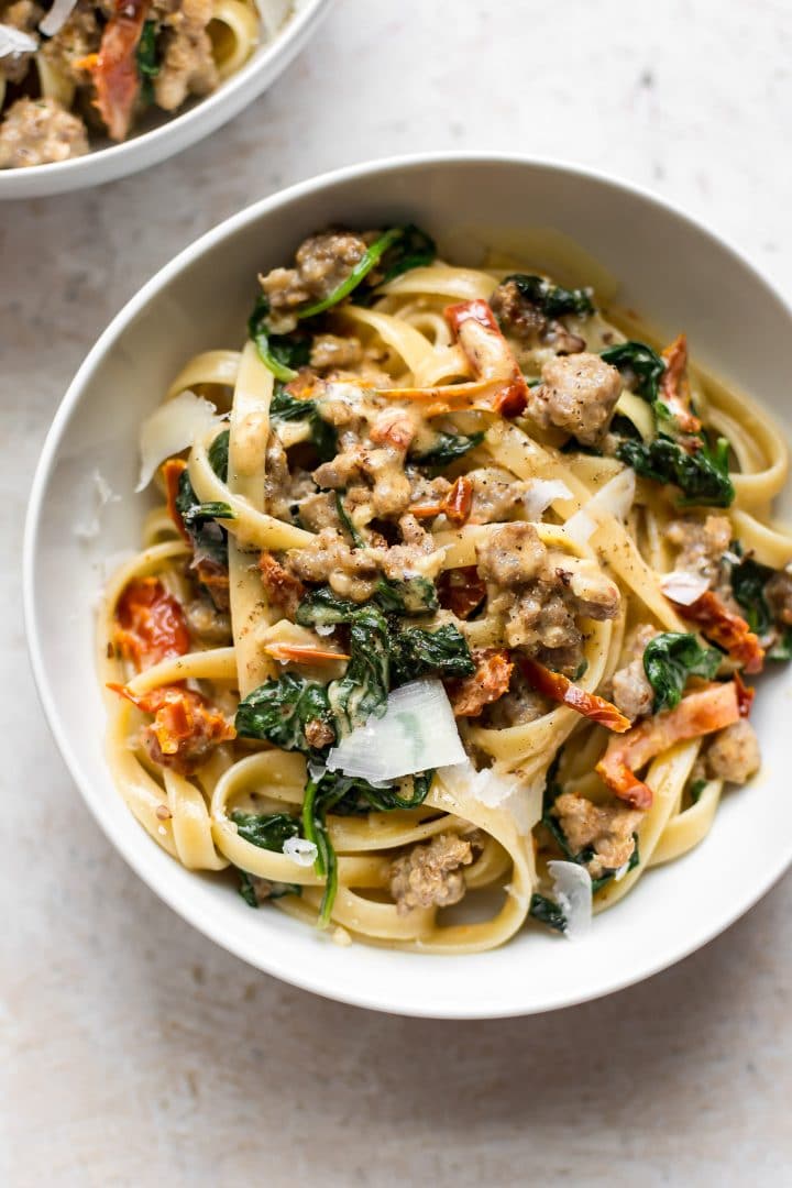 white bowl of creamy spinach sausage pasta in a Tuscan cream sauce