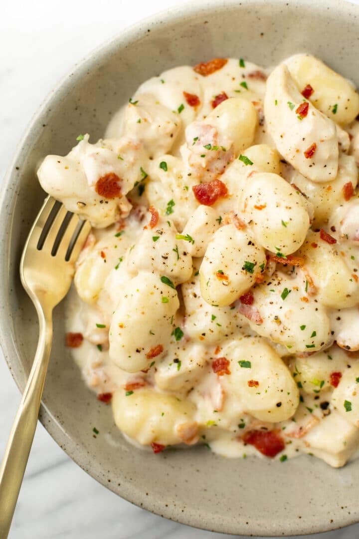 a bowl of chicken bacon gnocchi with a fork