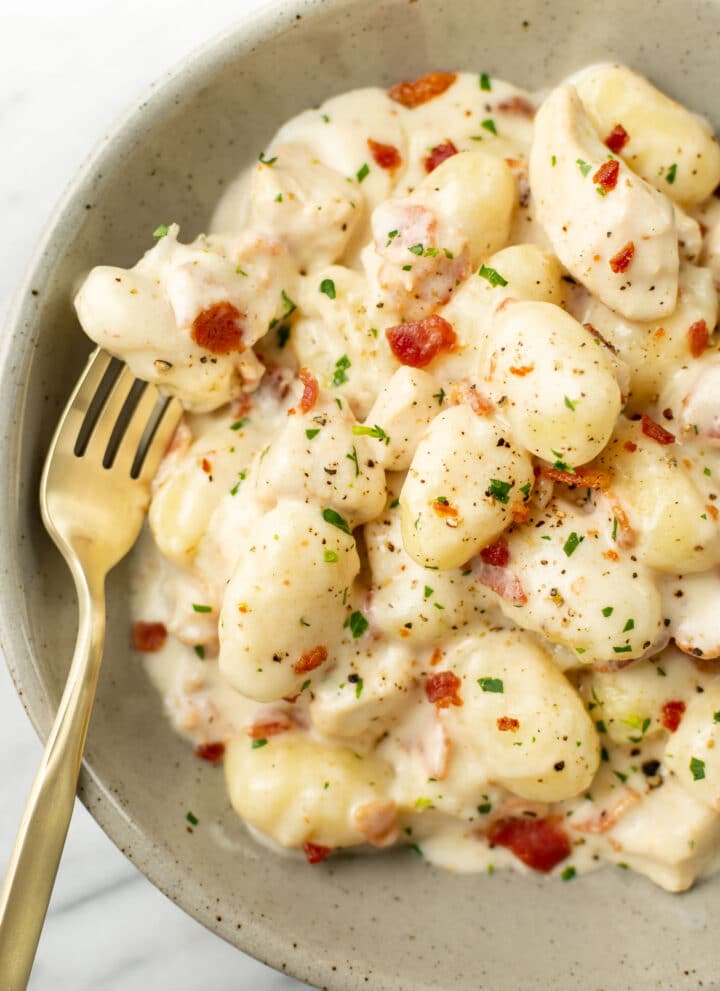 a bowl of chicken bacon gnocchi with a fork