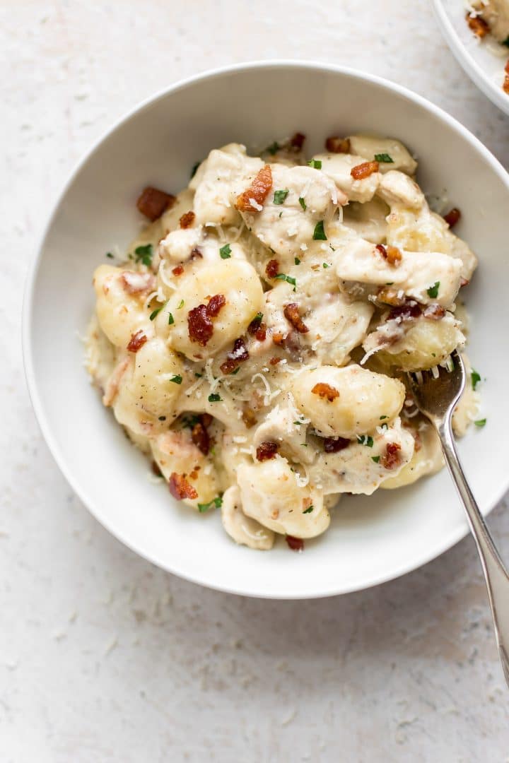 bowl of creamy bacon chicken gnocchi in a white bowl with a fork