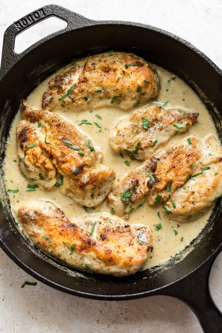 close-up of easy white wine chicken in a creamy sauce in a cast iron pan