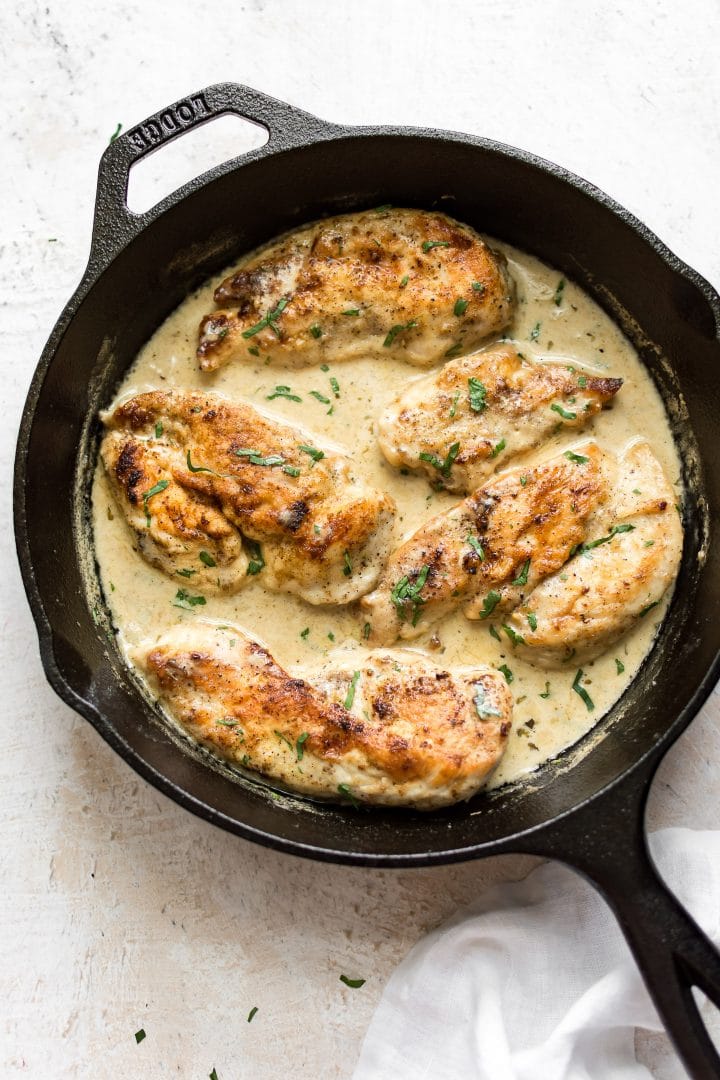 cast iron skillet with creamy white wine chicken and fresh parsley