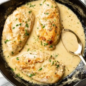 creamy white wine chicken in a skillet with a serving spoon