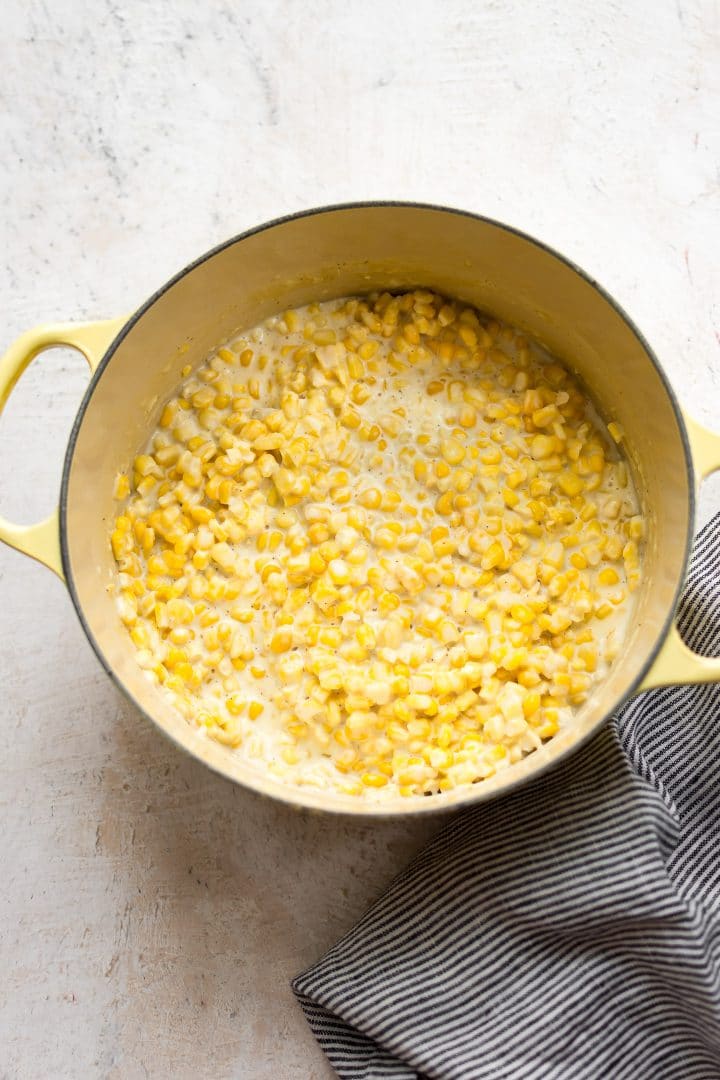 yellow pot with homemade creamed corn beside a cloth napkin