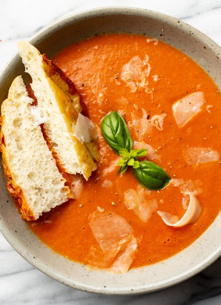 a bowl of tomato soup with bread