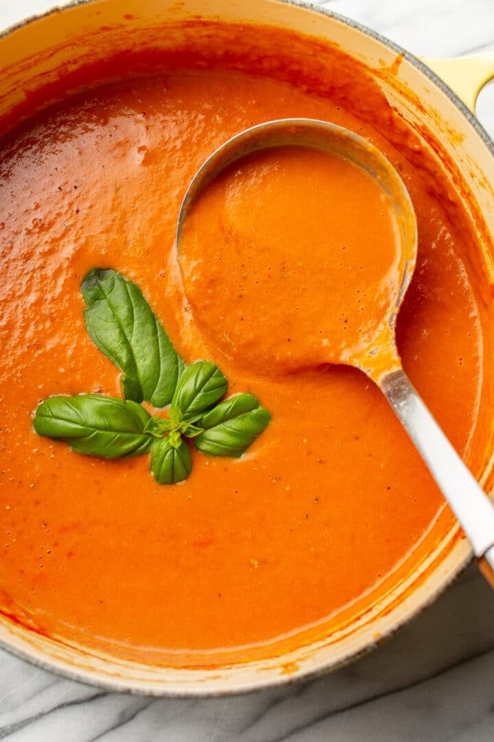 a pot of tomato soup with a ladle