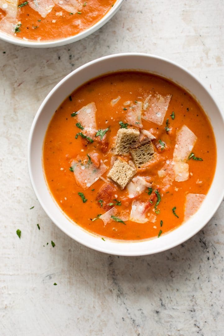 bowl of creamy tomato soup topped with croutons and parmesan