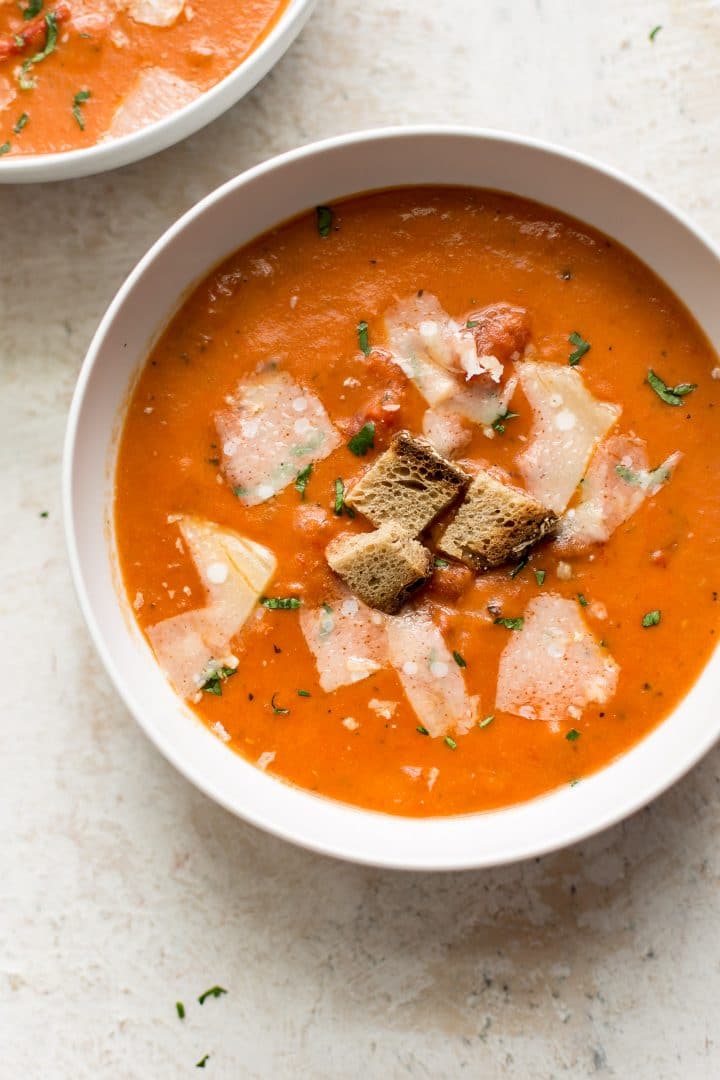 close-up of a white bowl of the best tomato soup with croutons
