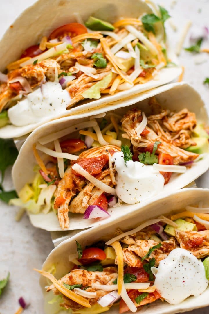 close-up of three Instant Pot chicken tacos topped with sour cream