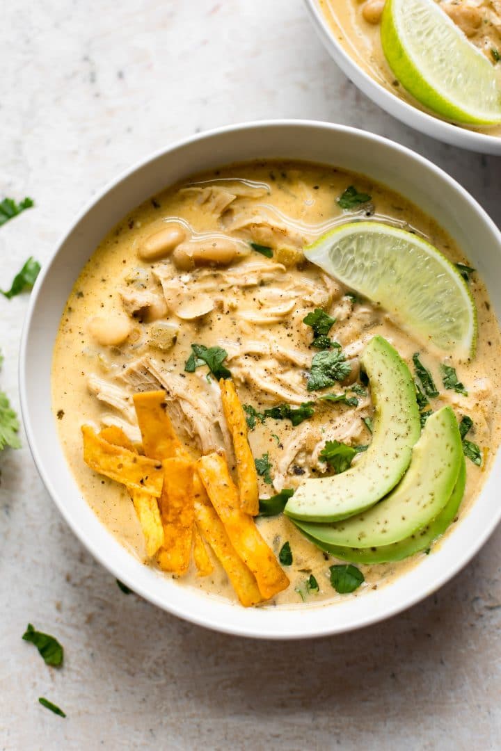bowl of Instant Pot easy white chicken chili with avocado, lime, and tortilla chips