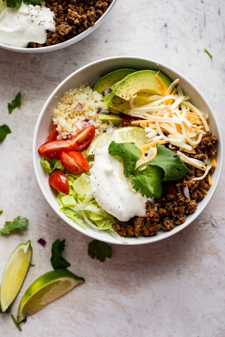 white bowl with low-carb taco bowl recipe next to lime wedges