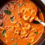 a ladle in a pot of tomato tortellini soup