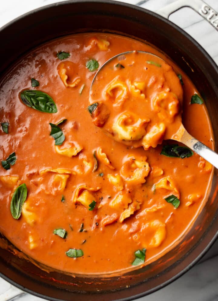a ladle in a pot of tomato tortellini soup