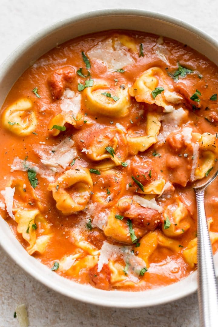 close-up of a bowl of easy creamy tomato tortellini soup with a spoon