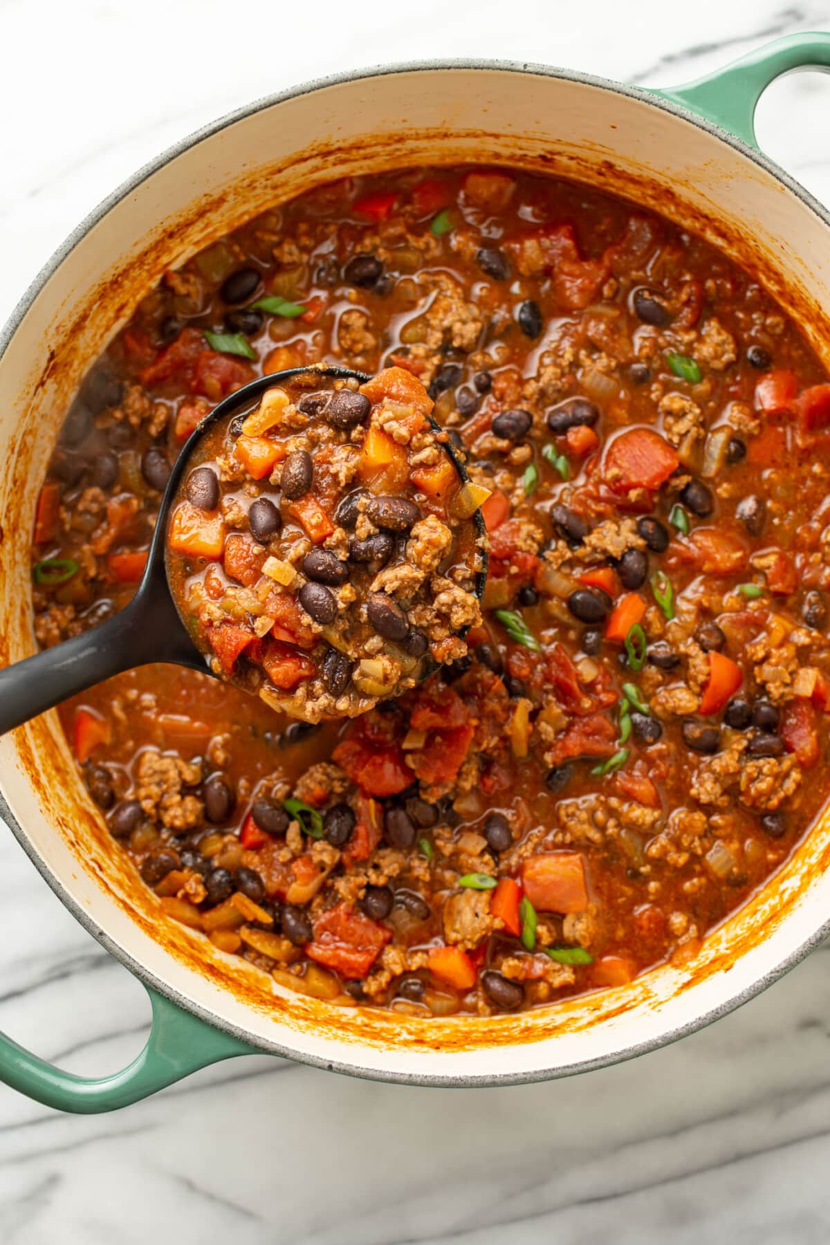 a pot of black bean chili with a ladle