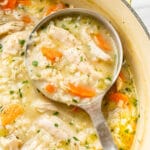 a ladle with chicken and rice soup