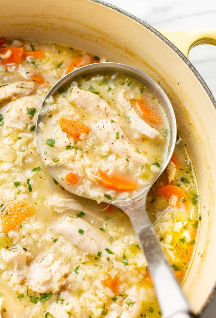 a ladle with chicken and rice soup