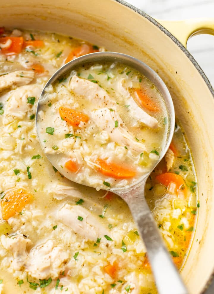 a ladle with chicken and rice soup