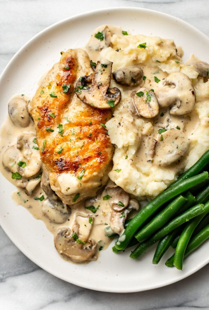 a plate with creamy mushroom chicken, green beans, and mashed potatoes
