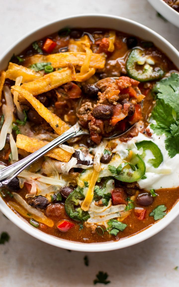 close-up of black bean chili in a white bowl with a spoon