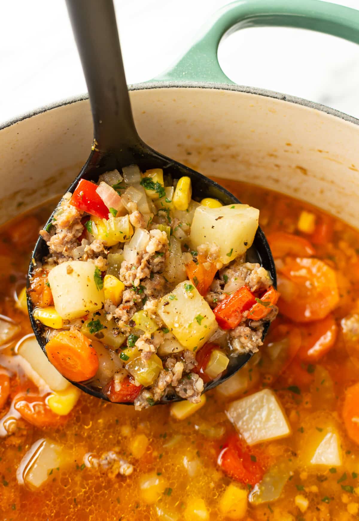 a ladle with italian sausage vegetable soup