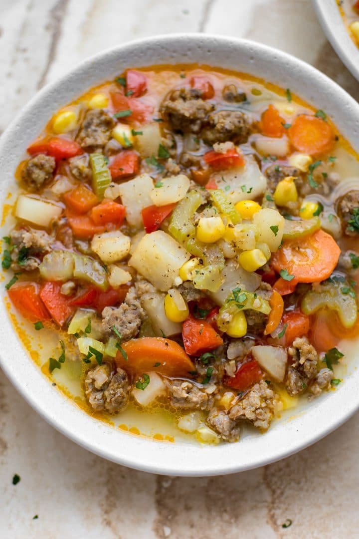 close-up of healthy sausage, corn, and potato soup in a white bowl