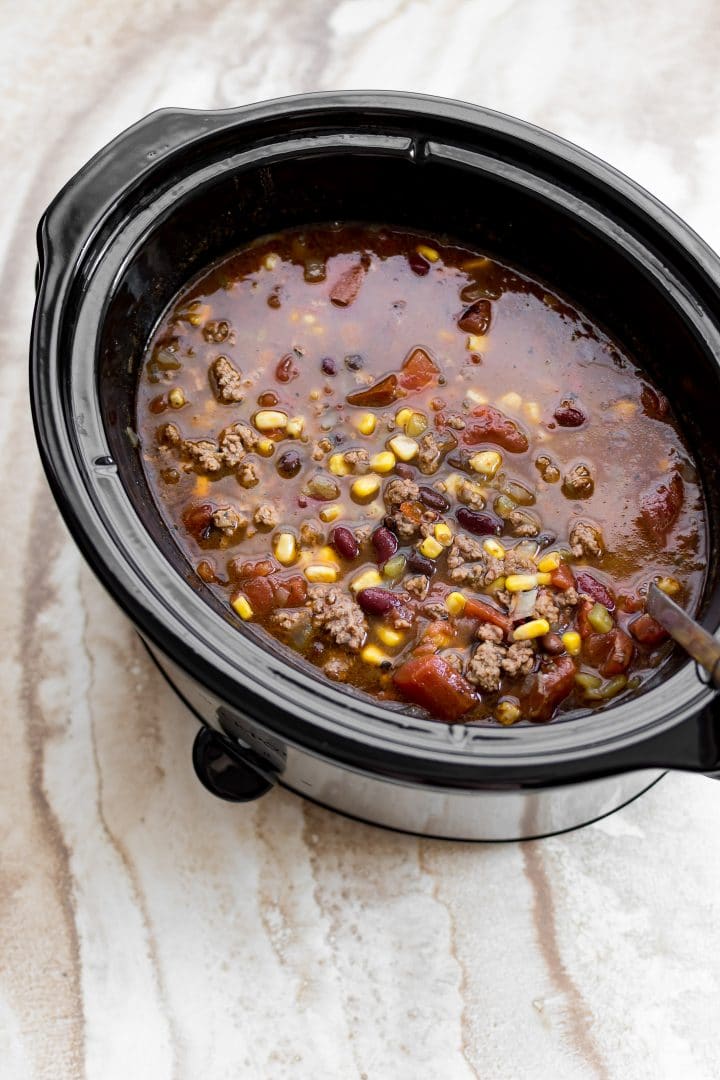 a crockpot slow cooker with simple taco soup and a ladle
