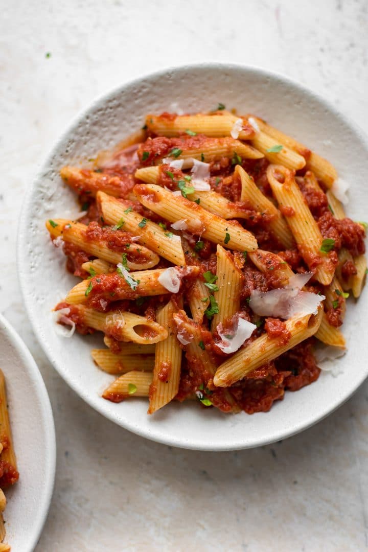 white bowl of vegetarian pasta arrabiata with grated parmesan