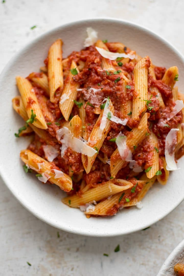 white bowl with penne and Italian arrabiata sauce with shaved parmesan