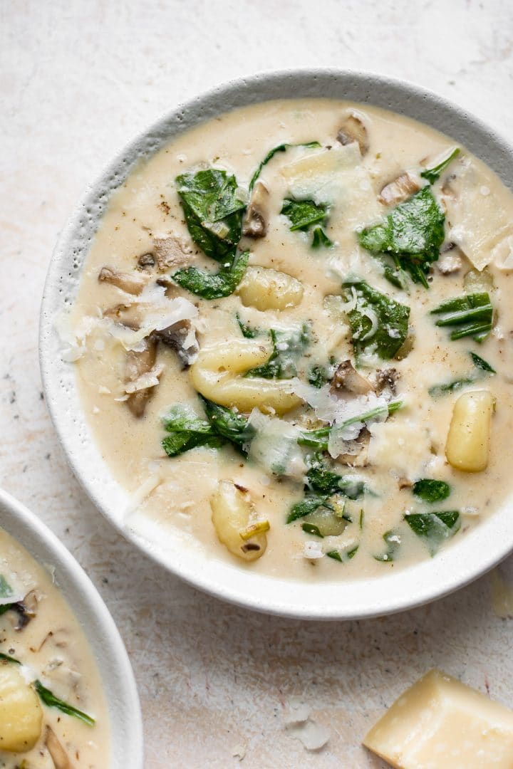 white bowl with creamy spinach gnocchi soup with mushrooms and spinach