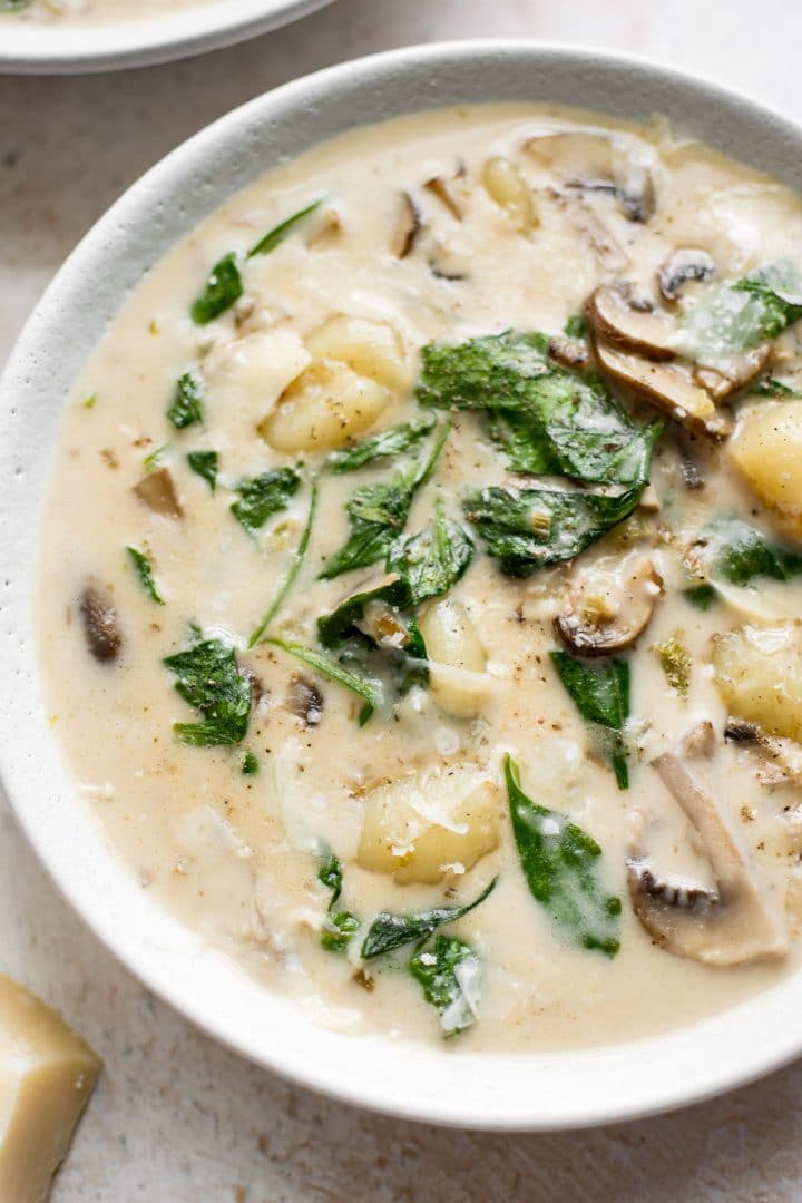close-up of creamy gnocchi soup with spinach, mushrooms, garlic, and a creamy broth