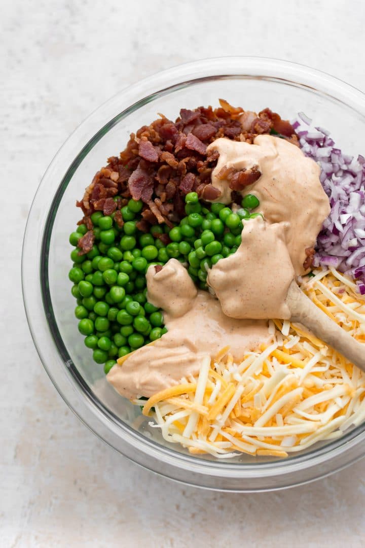 Creamy pea salad ingredients in a mixing bowl