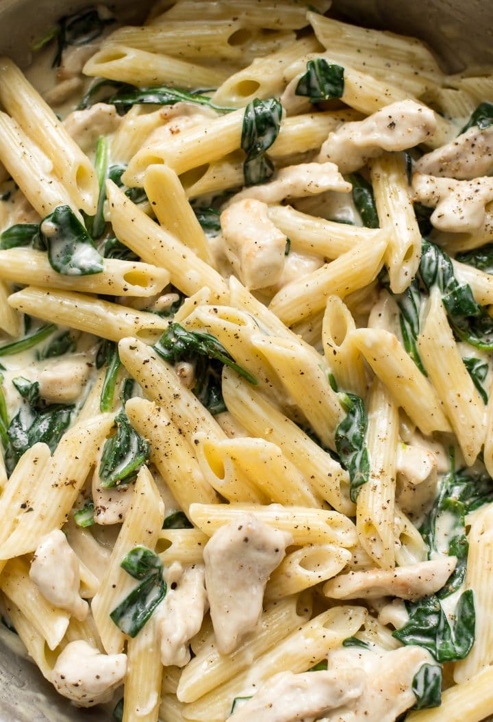 closeup of creamy chicken spinach pasta in pan