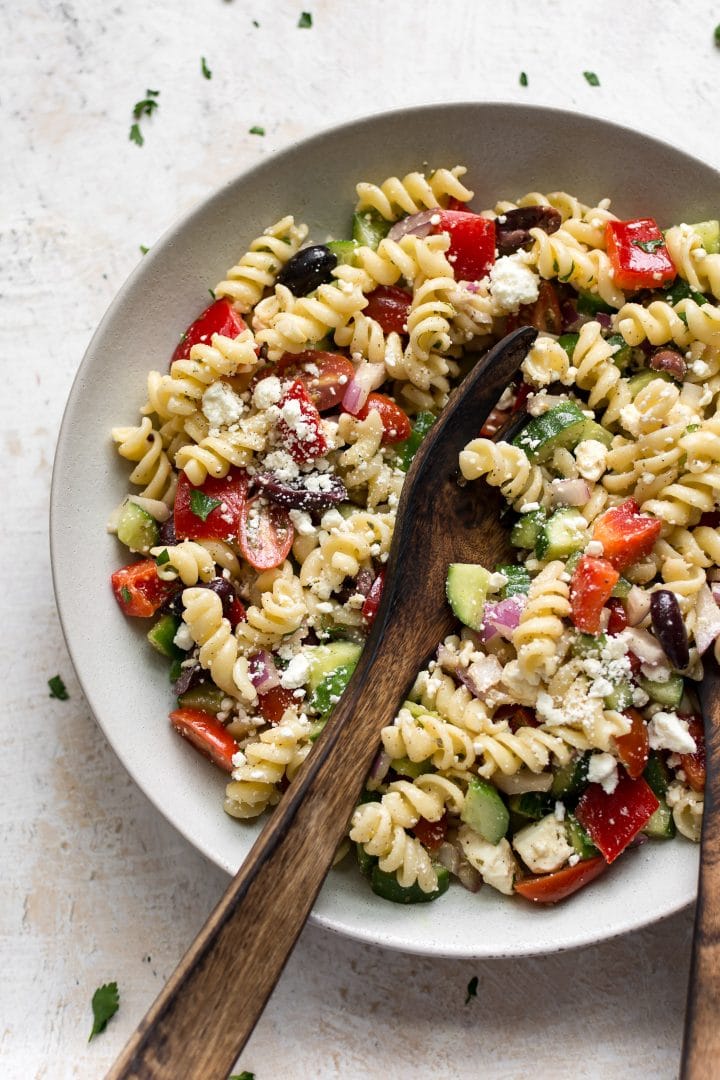 Greek pasta salad in a bowl with salad tongs