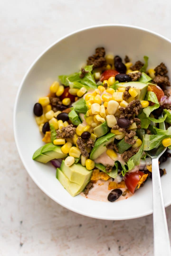 beef Doritos taco salad in a small white bowl with a fork
