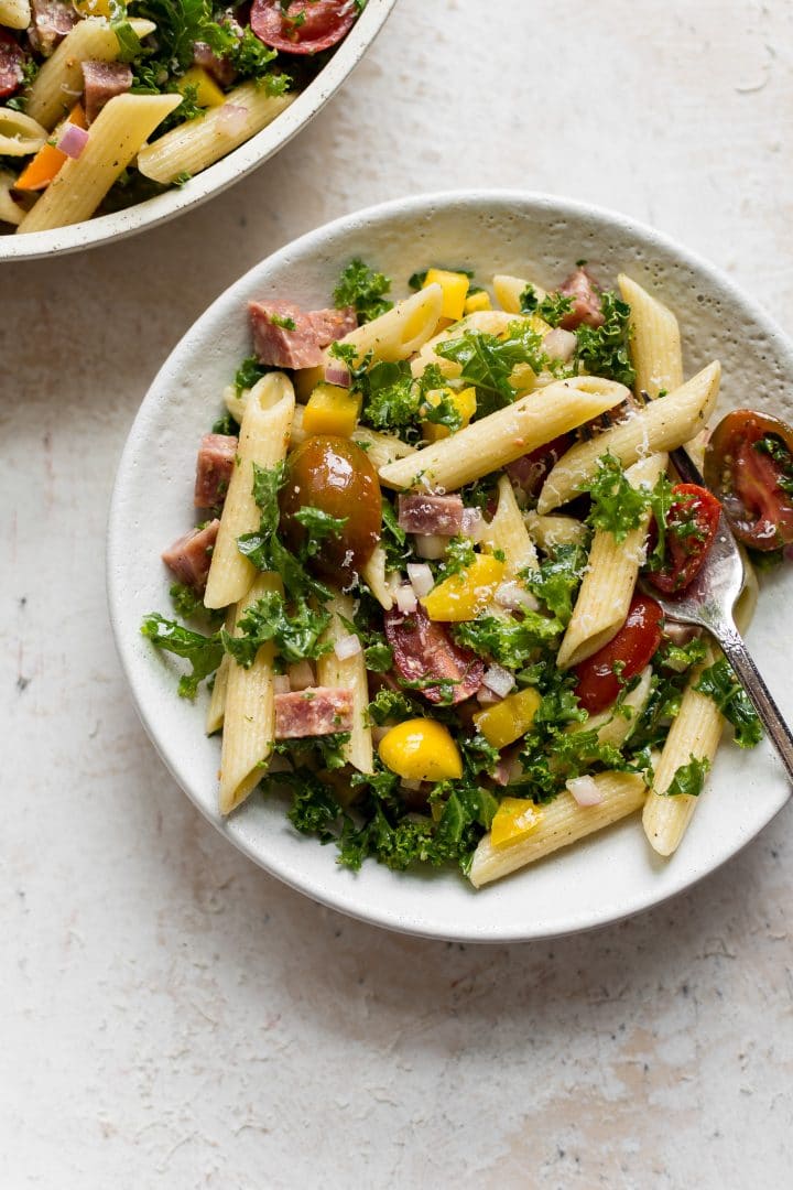 kale pasta salad in two small white bowls