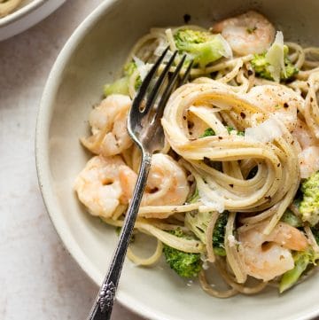 shrimp and broccoli pasta in a bowl with a fork
