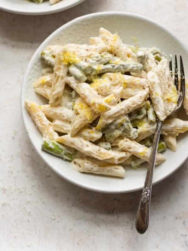 asparagus pasta with fork in two white bowls