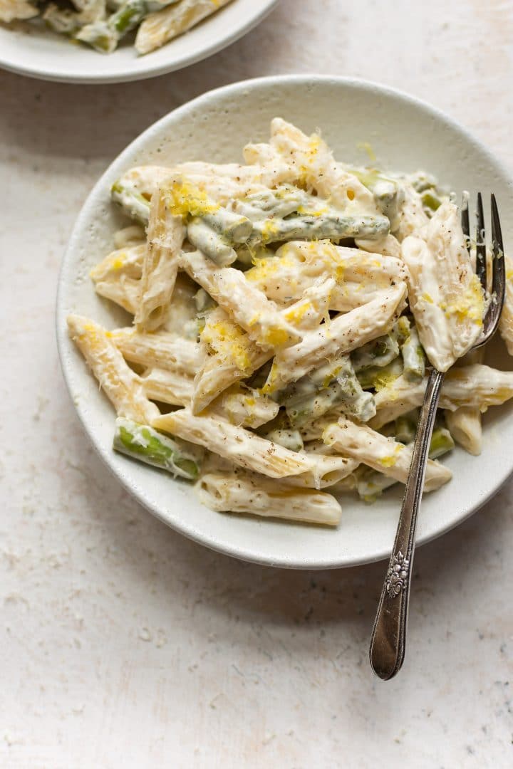 asparagus pasta with fork in two white bowls