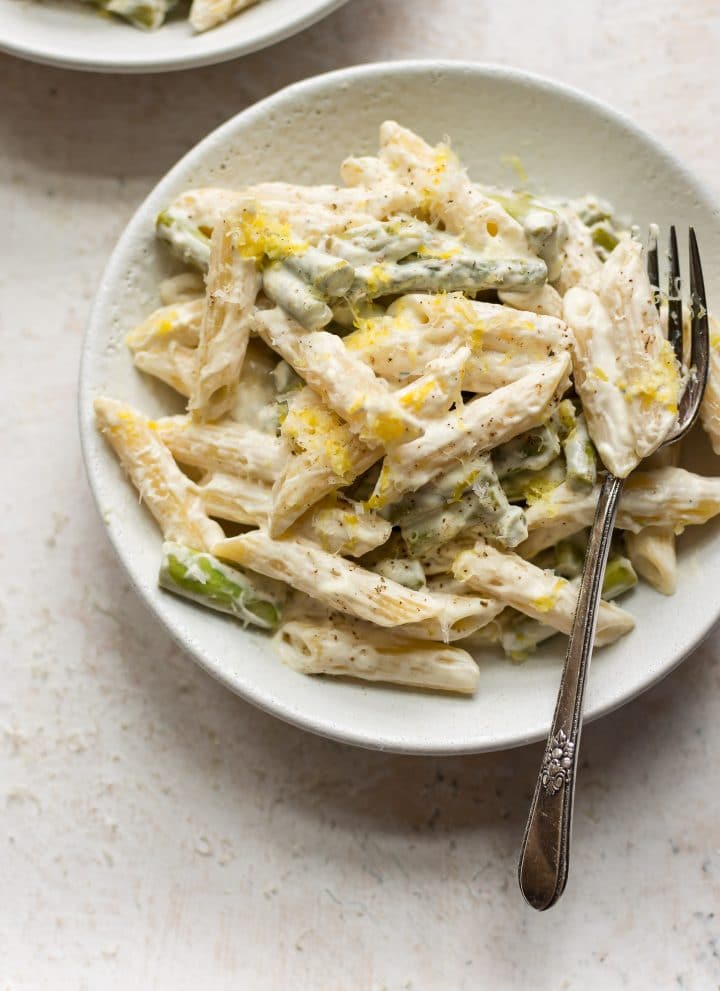 asparagus pasta with fork in two white bowls
