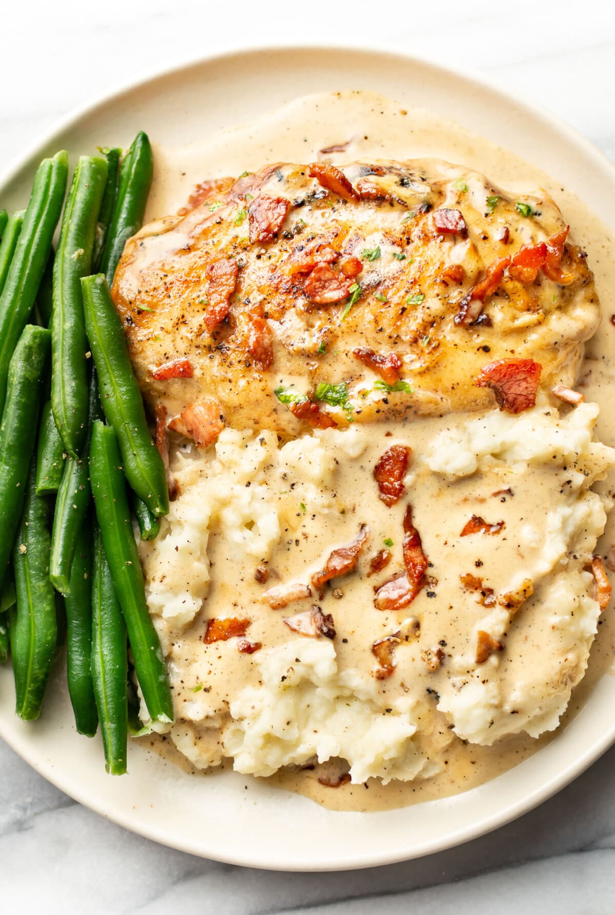 a plate with creamy bacon chicken, green beans, and mashed potatoes