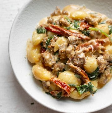 close-up in a white bowl of sausage gnocchi with Tuscan cream sauce