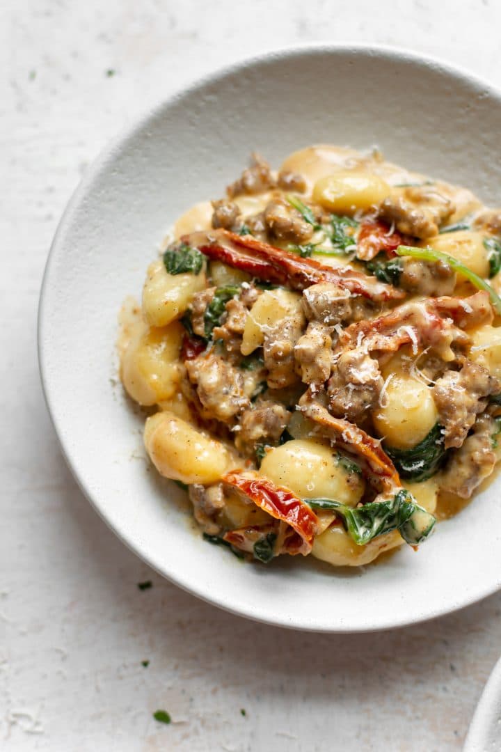 close-up in a white bowl of sausage gnocchi with Tuscan cream sauce